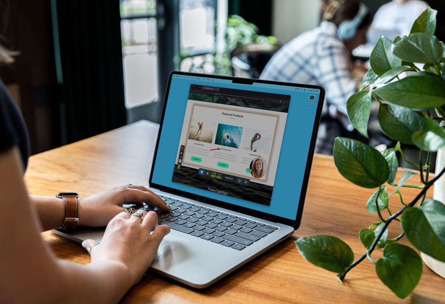 Photograph over the shoulder of a person working on a laptop at a coffeeshop. The screen shows a video message recorded with Snagit.