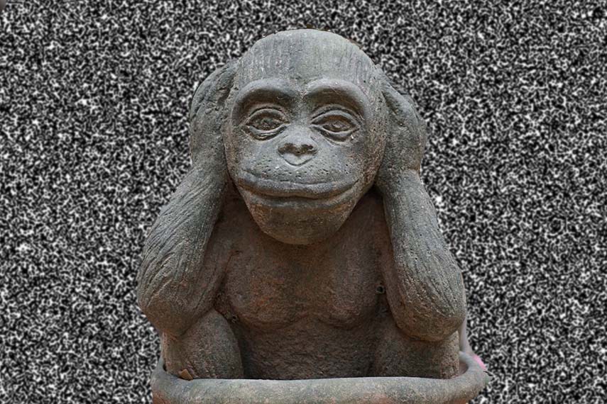 Une statue d'un singe se couvrant les oreilles avec ses mains