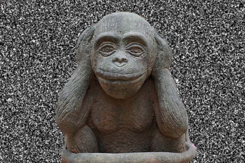 Une statue d'un singe se couvrant les oreilles avec ses mains
