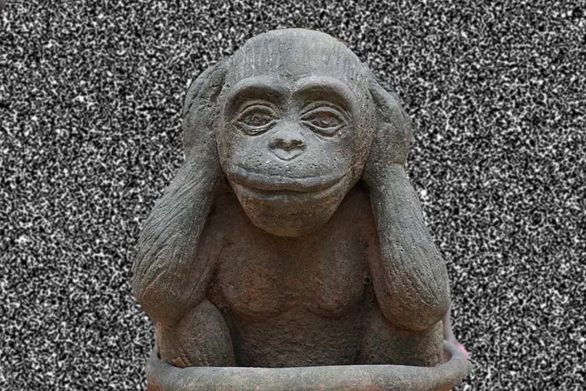 Une statue d'un singe se couvrant les oreilles avec ses mains